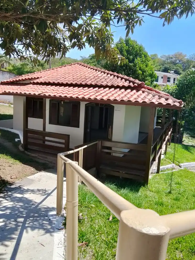 Varanda coberta da unidade com corrimão de madeira e vista para a área arborizada.