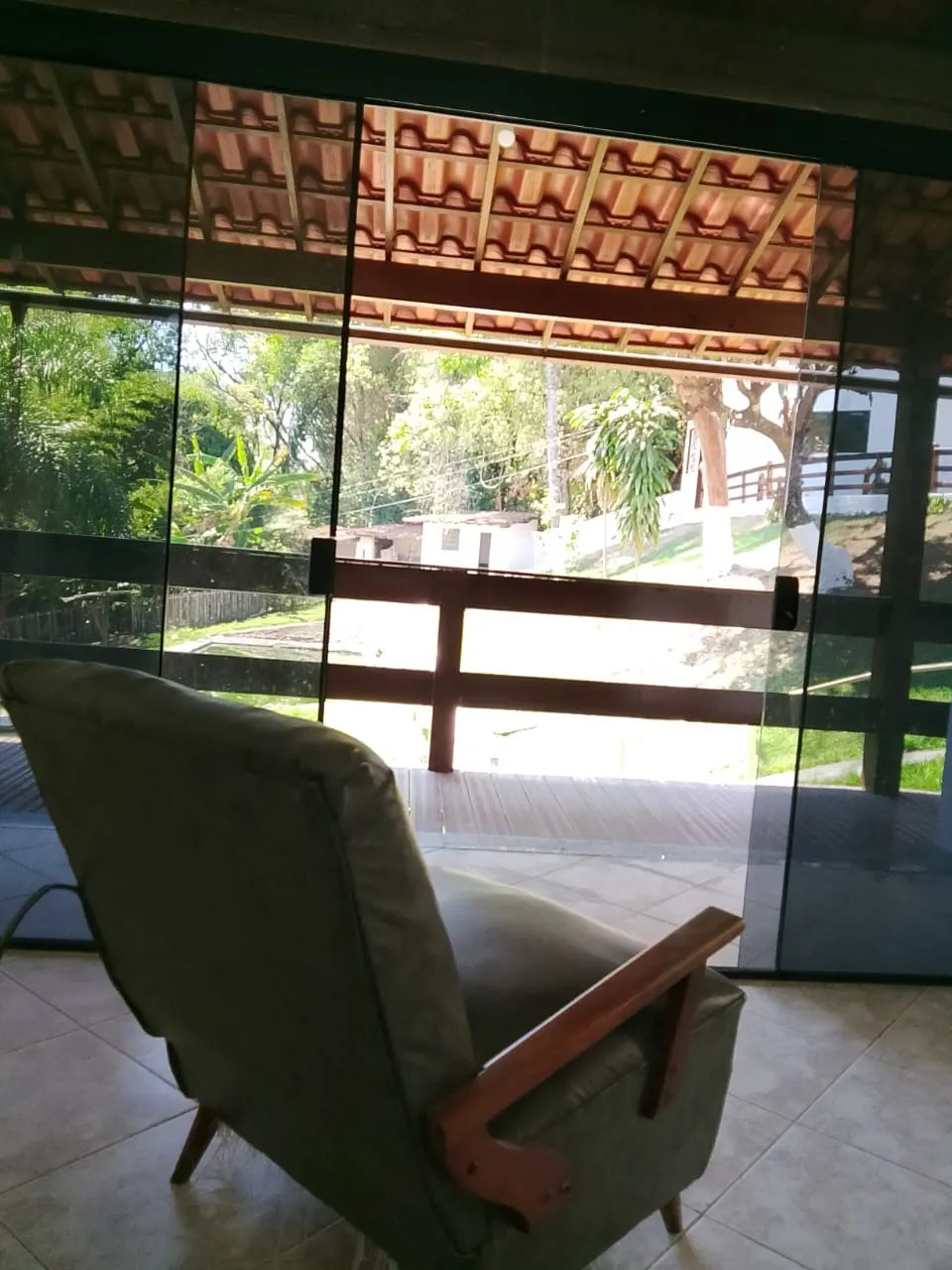Poltrona em ambiente coberto, com grade de proteção e vista para o gramado.