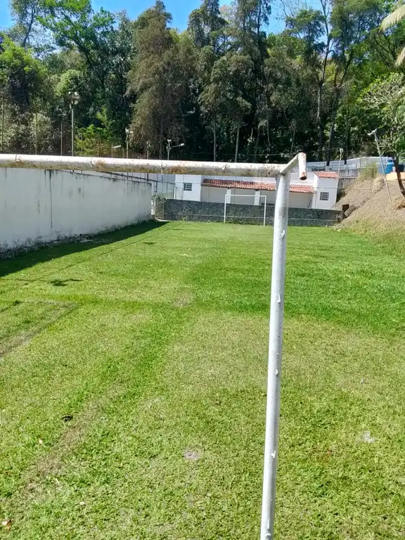 Campo gramado com traves e muro ao fundo.